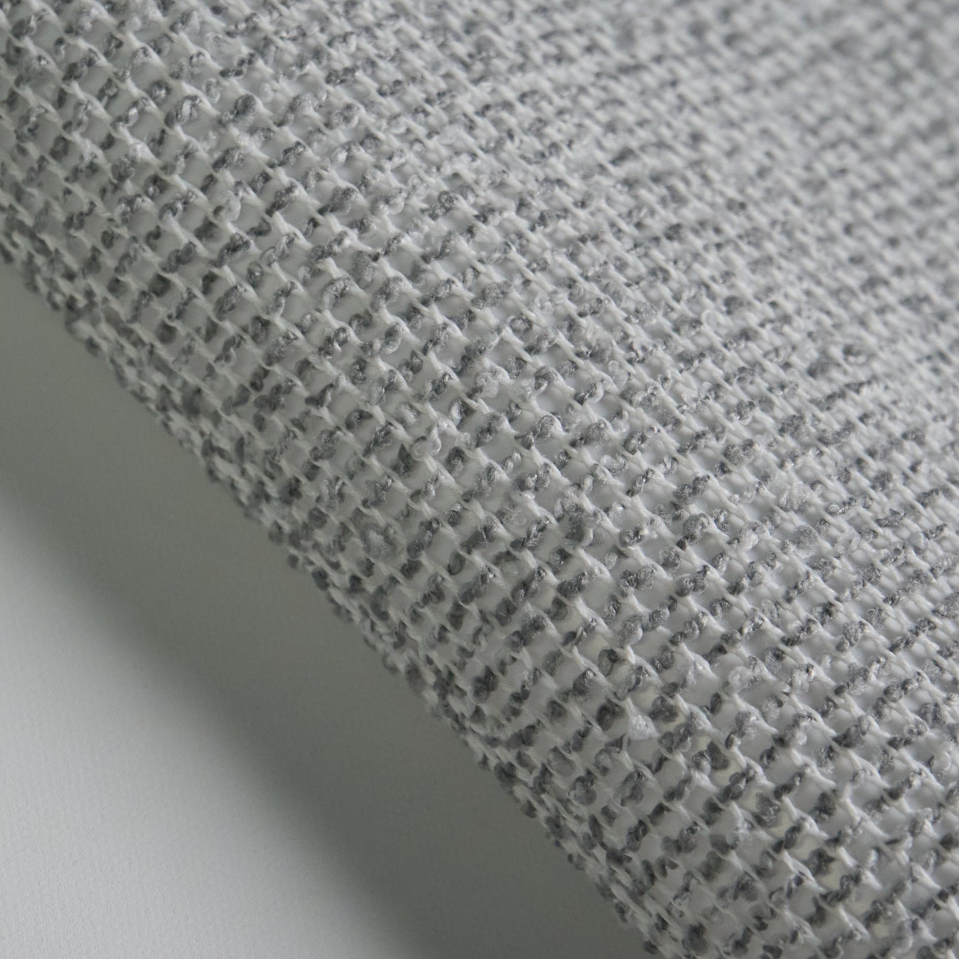Close-up of BOUCLE fabric texture in grey, highlighting the woven pattern and soft feel.